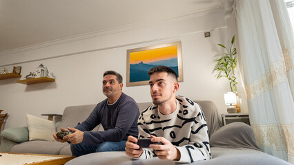 Father and son playing video games indoors