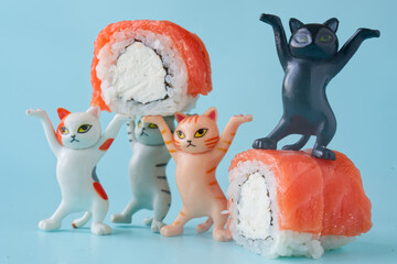 Team of cat figurines celebrating with fresh salmon and cream cheese sushi. Humorous scene for a food ordering service and menu design. Joy and delivery concept. Photo