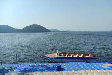 Boat at Chandil dam reservoir with blue water and green Dalma hills