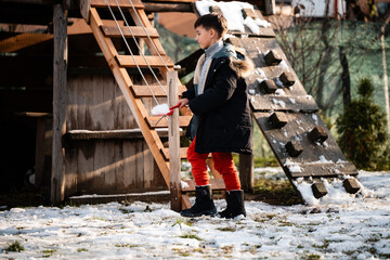 Boy playing with snow on wooden playground © Zoran Jesic