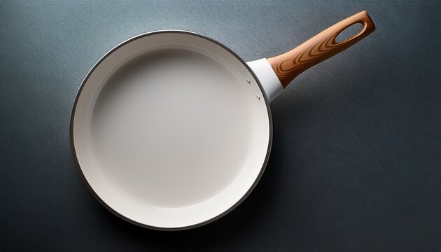 overhead view of a round white ceramic frying pan with a light brown wooden handle