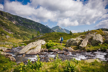 Man trekking along wild mountain stream in Austrian Alps mountains. Summer outdoor exploration and hiking in beautiful wilderness nature