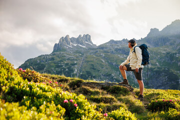 Hiker with backpack observing rocky peaks in Austrian Alps mountain. Scenic outdoor trekking and wanderlust exploration concept