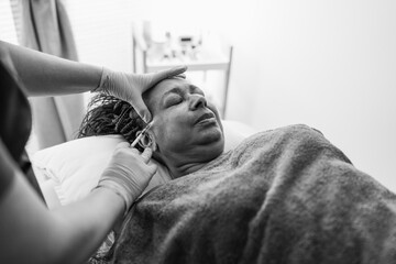 Senior african woman doing botox treatment inside private medical clinic - Beauty trends and anti...