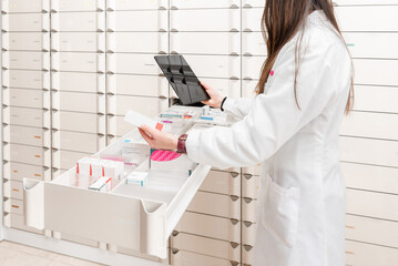close up of female Pharmacist using digital tablet checking medicine inventory in pharmacy drawer