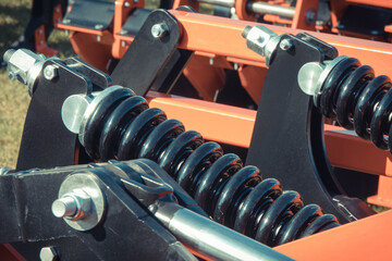 Steel black spring as part of heavy agricultural, industrial machine. Technology