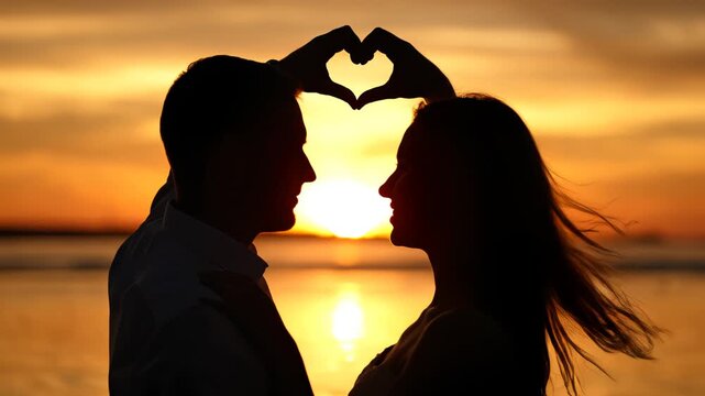 Couple forming heart shape at sunset