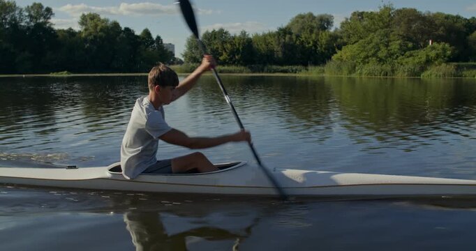 A rower actively paddles during kayaking training. A man rows along the river during kayak training.