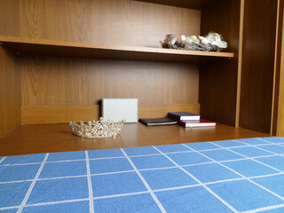 Silver crown resting on wooden shelf near notebooks, decorative symbolic still life composition.