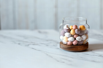 Easter chocolate Multi-Colored eggs in pastel colors in glass jar with copy space.