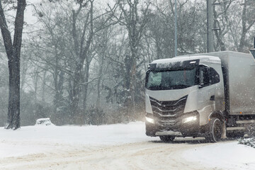 Winter logistics scene cargo truck driving heavy snowfall icy road forest city suburban urban landscape low visibility conditions. Scenic freight transport cold weather risk supply chain challenge