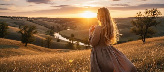 Woman Photographing Sunset Over Rolling Hills From Wheat Field, Flowing Dress And Windblown Hair, Warm Amber Light, Phone Held At ArmS Length, Sense Of Exploration And Creative Moment