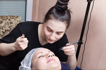Brunette woman getting eyelash extensions applied by a beautician