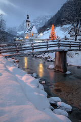 Winter Wonderland in Alps. Landscape image of the Bavarian Alps during Christmas time, with Parish Church of St. Sebastian located in Ramsau bei Berchtesgaden, Germany at beautiful winter sunset.