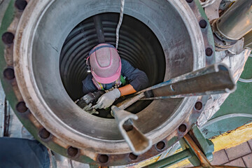 Top view male climbs up the stairs into the tank stainless chemical area confined