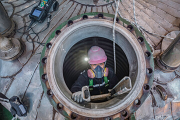 Top view male climbs up the stairs into the tank stainless chemical area confined