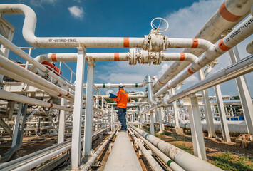 Male worker inspection at steel long pipes and pipe elbow in station oil factory during refinery valve of visual check record pipeline
