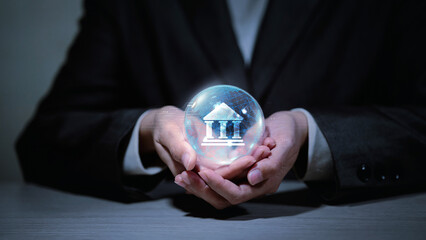 Businessman hands holding virtual bank icon with global network inside glowing sphere.