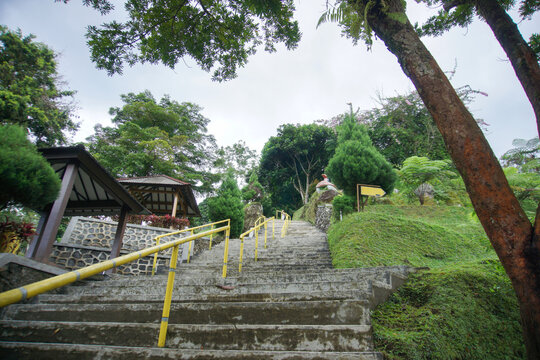 Stone stairway with yellow railings leading through lush green park landscape