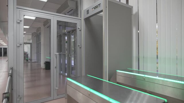Entrance hall features turnstile and metal detector frame beside glass doors. Security layout ensures controlled access and visitor safety