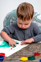 Young child enjoying finger painting activity, using hands and bright colors to express creativity, curiosity, and joyful early development at home.