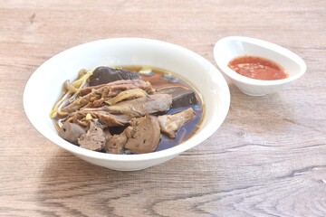 boiled slice duck meat with liver and blood in black soybean herb soup in bowl dipping spicy sour chili sauce