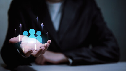 Businessman holding virtual people icons with upward arrows for human resources growth.