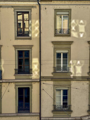 Obraz premium Sunlit Apartment Windows On Historic Urban Facade