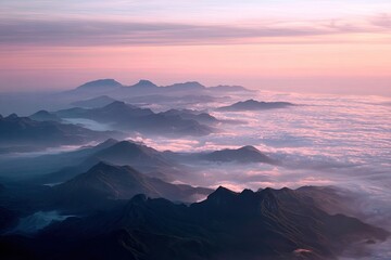 Obraz premium Aerial view of mountain peaks emerging from a sea of clouds, illuminated by a pink and purple sunrise
