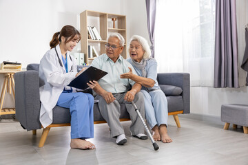 Young female doctor visiting senior couple at home explaining medical report on clipboard with positive care, happy elderly patients listening to advice sitting on comfortable sofa in bright room