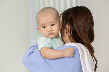 Adorable asian baby feeling calm while resting on mother shoulder looking safe with serious face expression concept childhood parenting care love family bonding