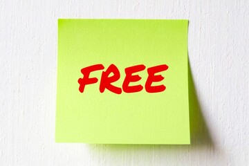 Yellow note paper with word Free on the white wall.