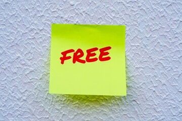 Yellow note paper with word Free on the white wall.