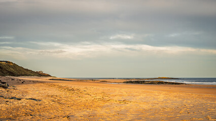 North end of Embleton Beach in Embleton Bay, which is a long stretch of sand overlooked by the dramatic ruins of Dunstanburgh Castle located on the North Sea coast in the National Landscape (AONB)