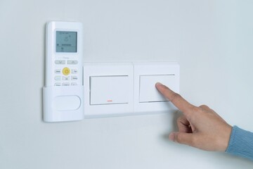 A person's hand turning off a light switch. Conserve electricity, energy saving and practice energy efficiency at home concept.