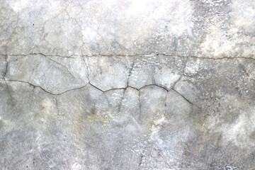 The surface of an old, dirty, cracked gray cement wall.