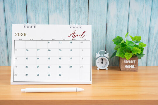 April Monthly desk calendar for 2026 year and alarm clock.