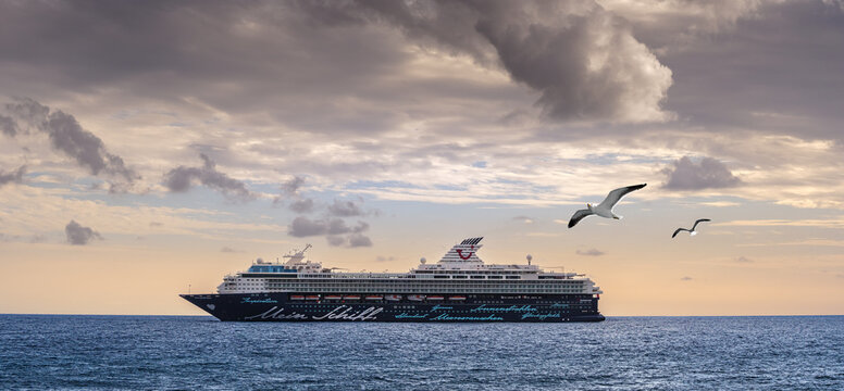 Canary islands, Spain - November 11, 2021: Luxury voyage on a board of the ocean cruise liner. Passenger ship Mein Schiff Herz near the coast of Tenerife island on sunset, travel cruising company TUI.