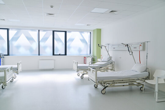 Bright and clean hospital ward with empty beds and large windows during daytime