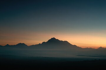 Silhouette of a jagged mountain range against a vibrant orange and blue gradient sunset sky