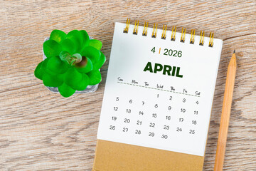 April 2026 monthly desk calendar and pencil with plant pot decoration.