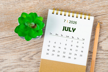 July 2026 monthly desk calendar and pencil with plant pot decoration.