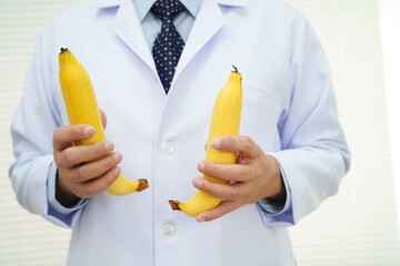 Male doctor stands holding a banana, penis health.