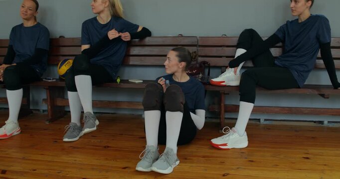 The girls' team talks after the game, one of them drinks water from a bottle while sitting on the floor.
