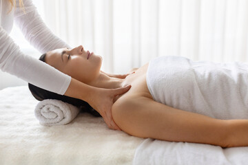 Obraz premium Young beautiful woman relaxing during professional spa neck and shoulder massage, lying on treatment bed, calm wellness atmosphere focused on beauty care, selfcare, and relaxation