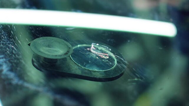 Windshield repair. Repair of a chip on the windshield of a car. Mounted windshield repair bridge holds resin applicators securely over the crack. Bridge tool for injecting resin in damaged windshield.