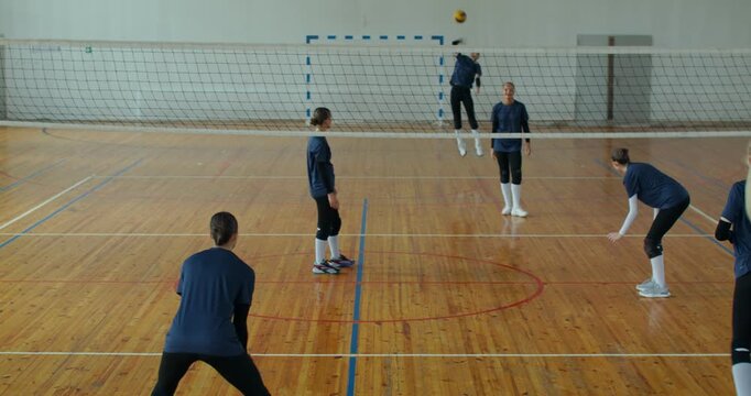 A girl scores a point against the opposing team during a volleyball game. In a 3-on-3 format, the girls actively serve, return, and pass the ball to each other, creating a dynamic game on the court.