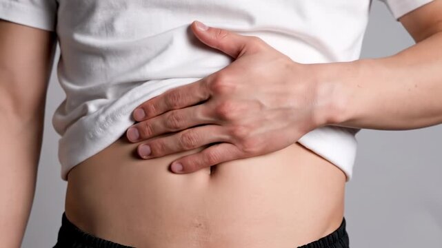 Man feeling his stomach with hand, experiencing discomfort, pain, or bloating, a medical concept footage