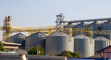 Steel grain storage silos with a conical bottom can be used for various purposes. Industrial facilities of feed and flour mills. Against the backdrop of a beautiful sky with clouds.
