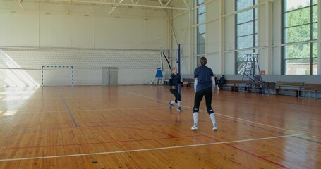 Two girls warm up with the ball before training, two more volleyball players approach them, greet them, and start training.